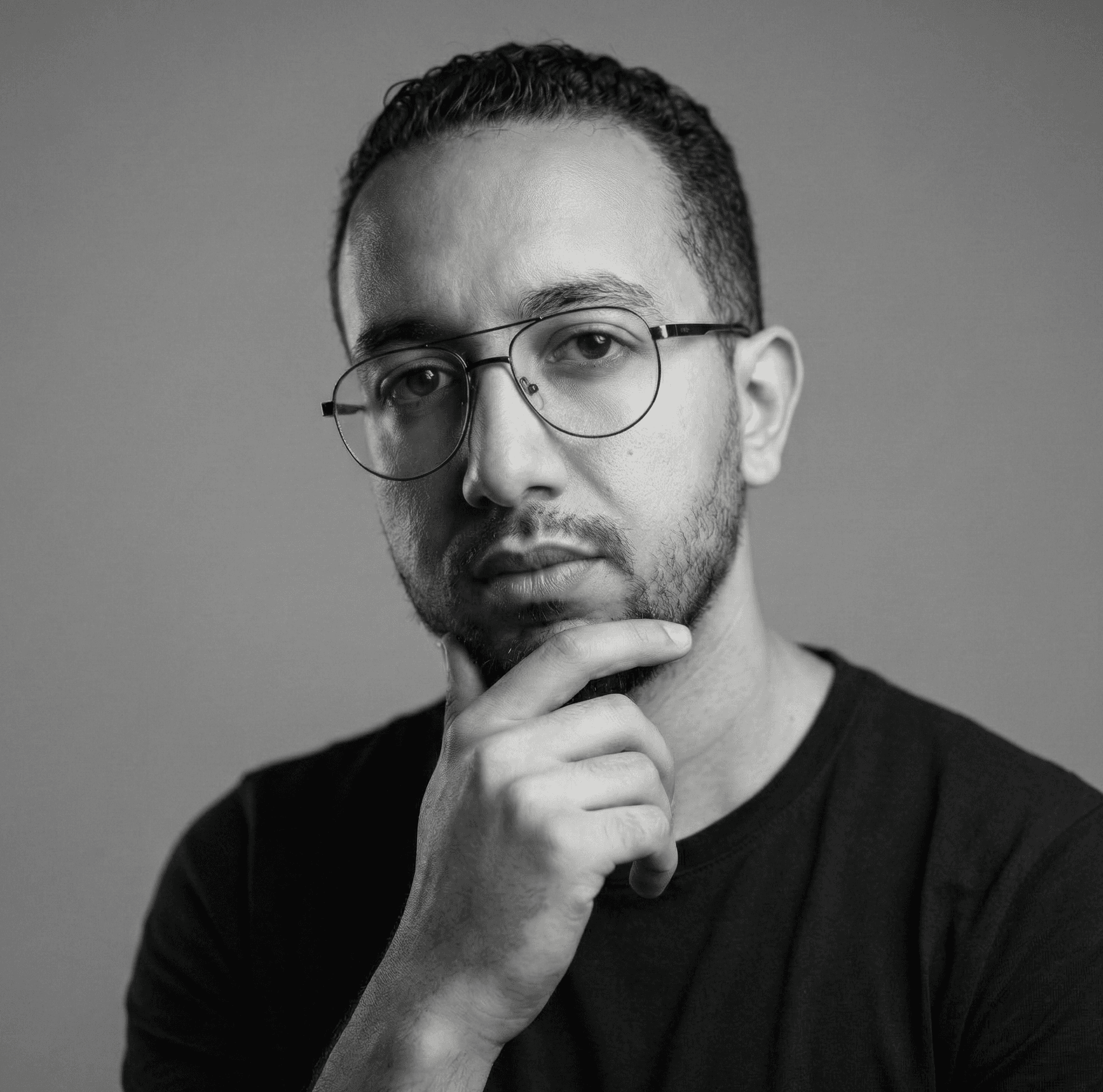 Portrait of a man in a plain white t-shirt against a grey wall
